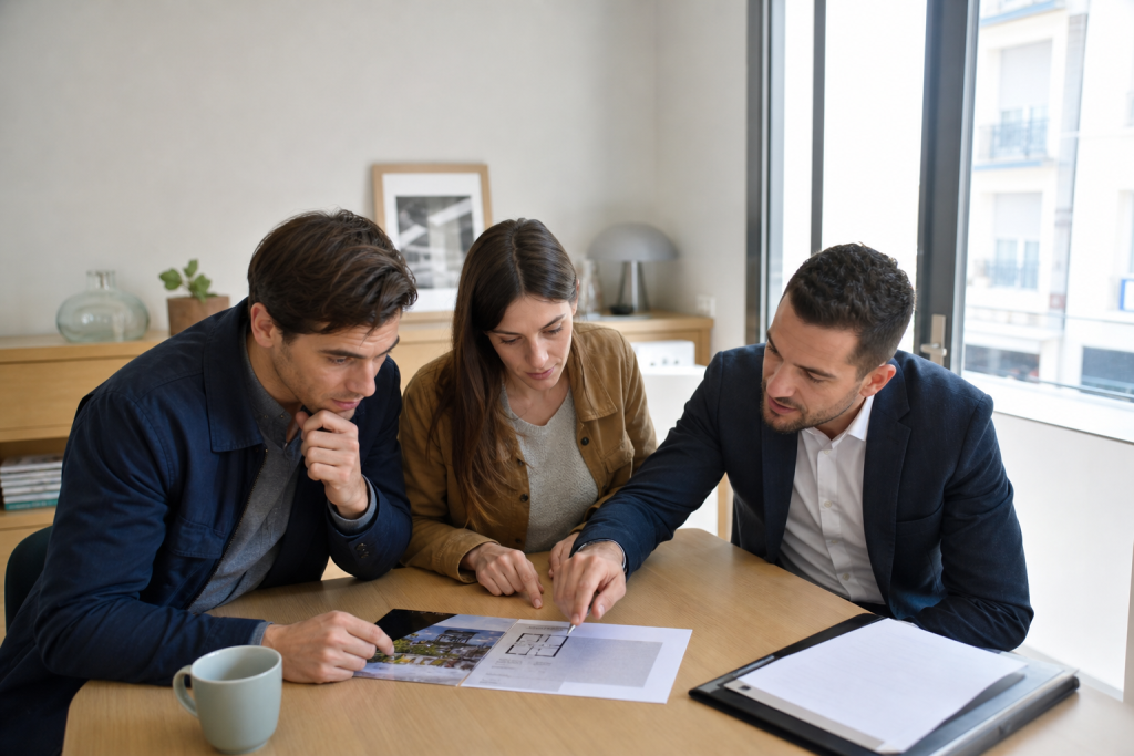trois personnes examinant des plans sur une table